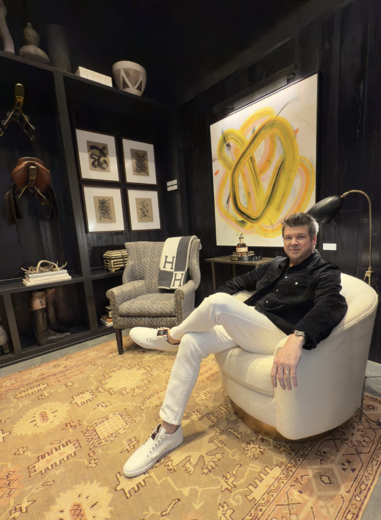 Contemporary abstract artist Chris Artabasy seated in a gallery with his abstract oil painting